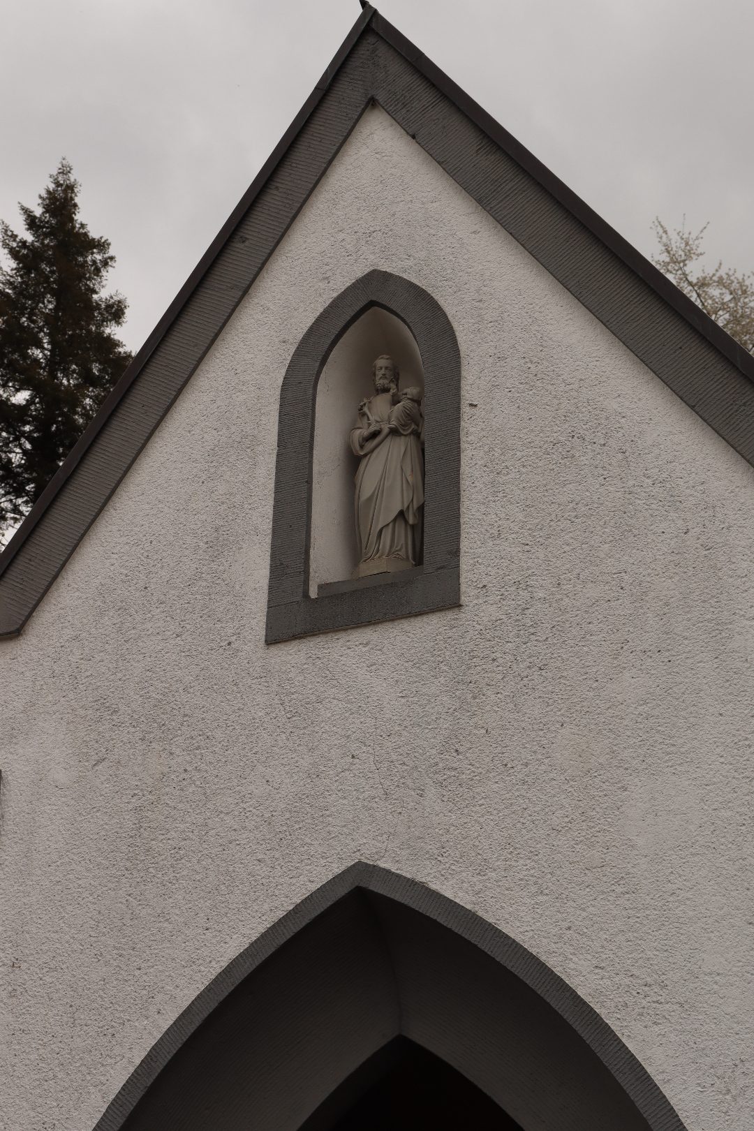 Giebel der Pestkapelle mit neogotischer Heiligennische bei bewölktem Himmel